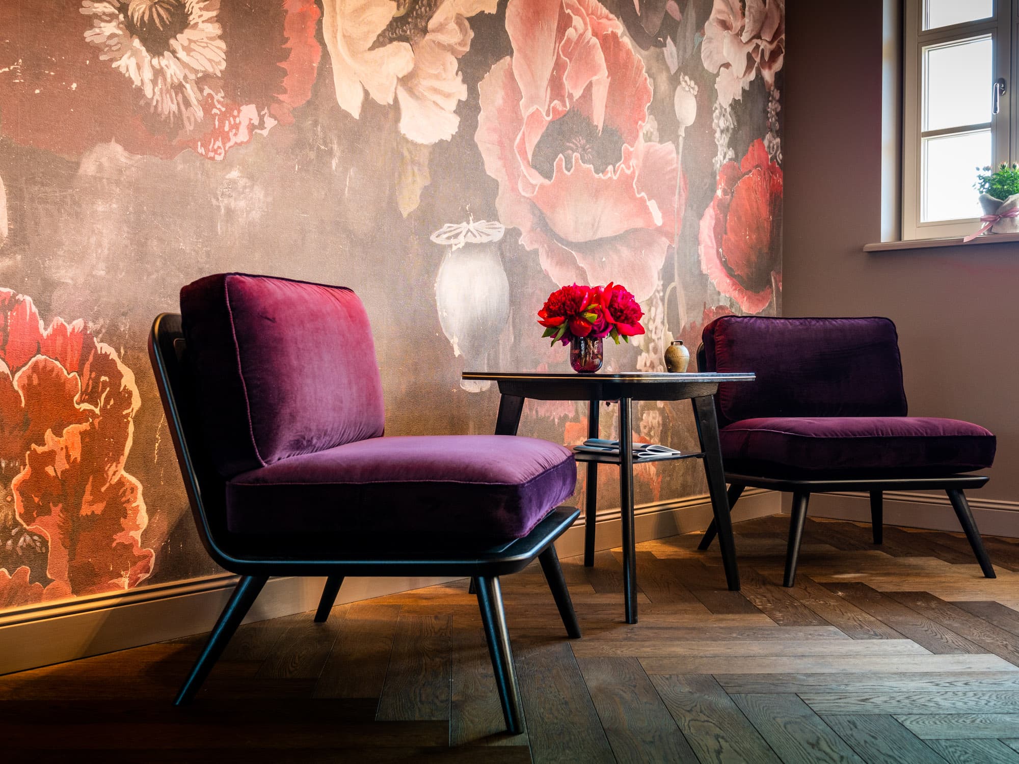 Alpenloge – Interior mit violetten Sesseln vor floraler Wandmalerei